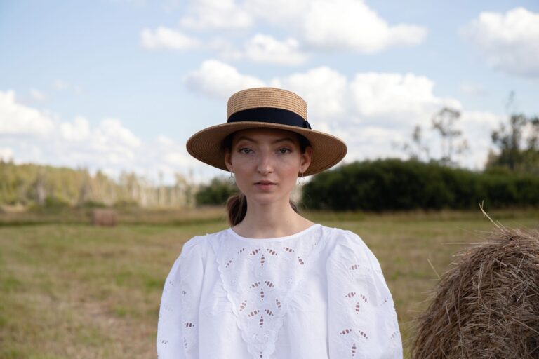 A classic flat-brimmed straw boater hat displayed against a light background