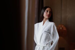 A structured long robe with wide lapel collar laid flat on a surface, showing fabric weight and clean tailoring