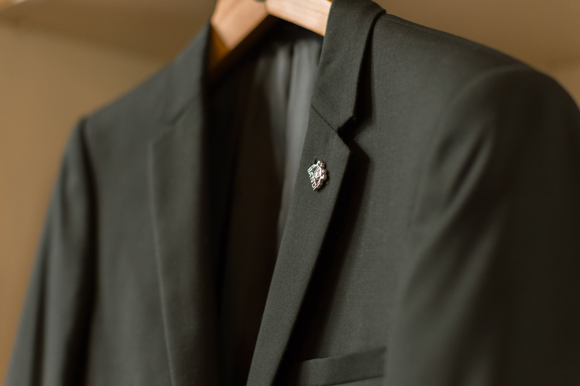 Minimalist metal bar accessory pinned to the lapel of a tailored blazer