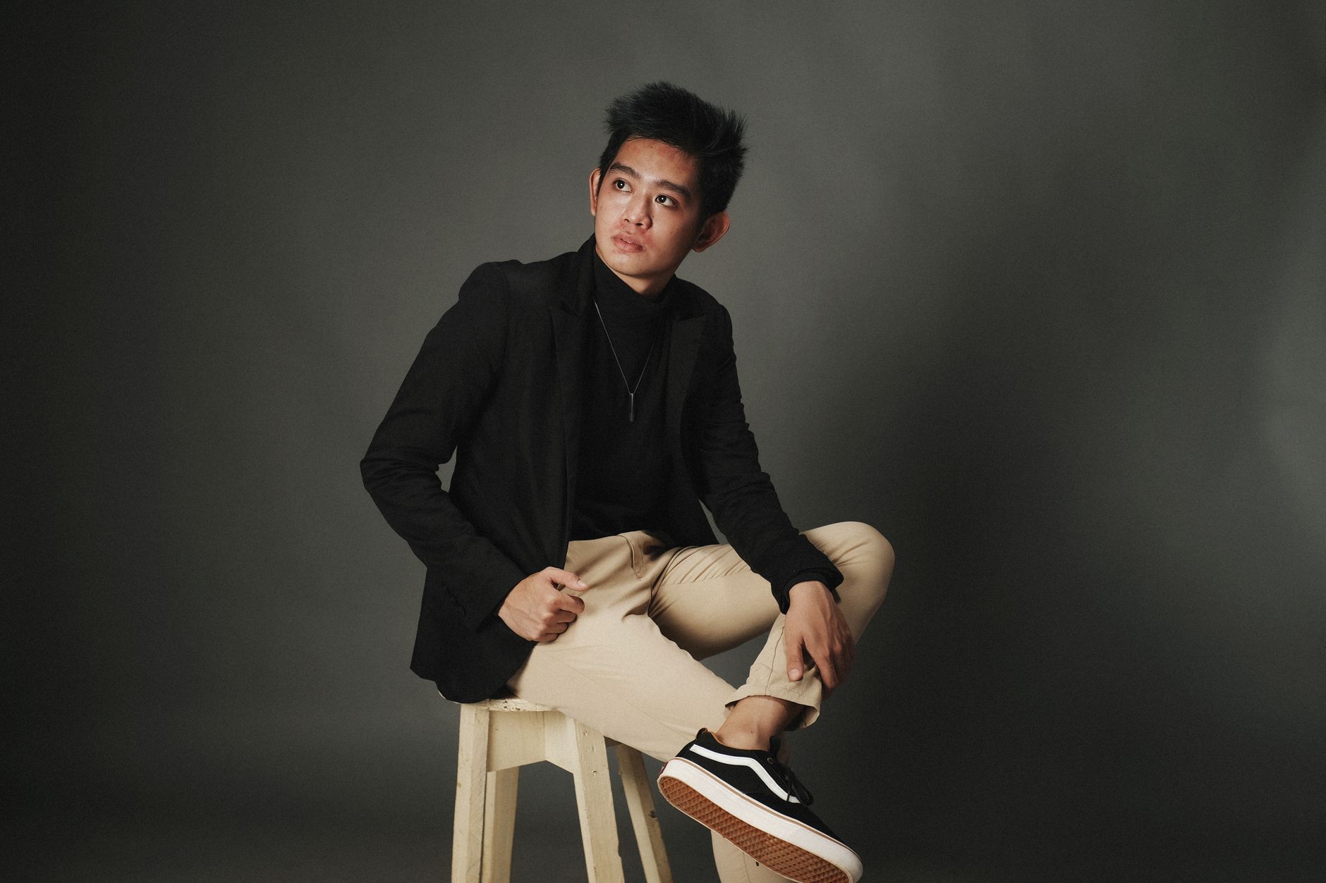 A model in a clean white shirt and structured blazer with a simple pale neckpiece at the collar