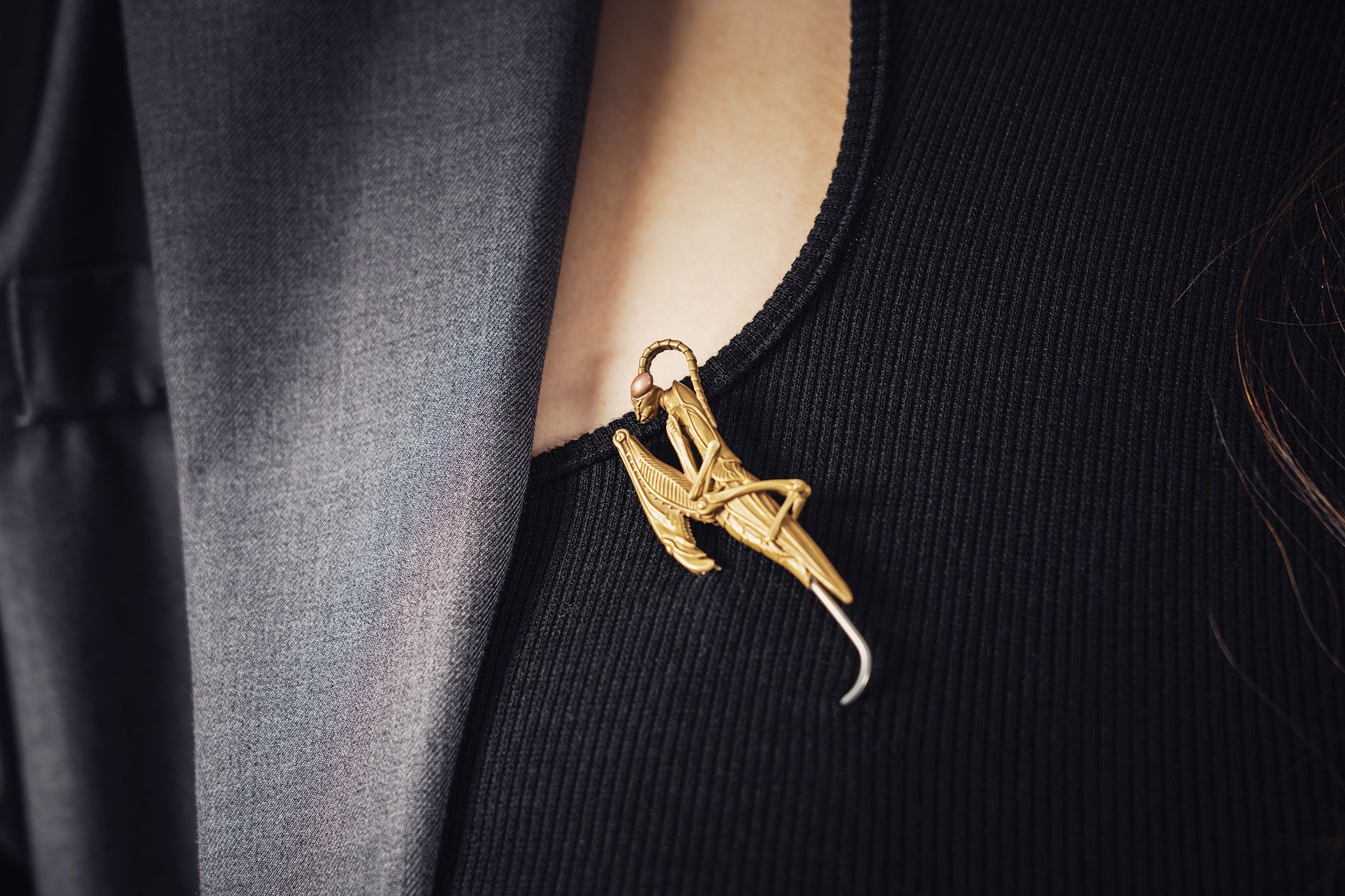 A gold bar collar pin resting across the collar points of a white dress shirt