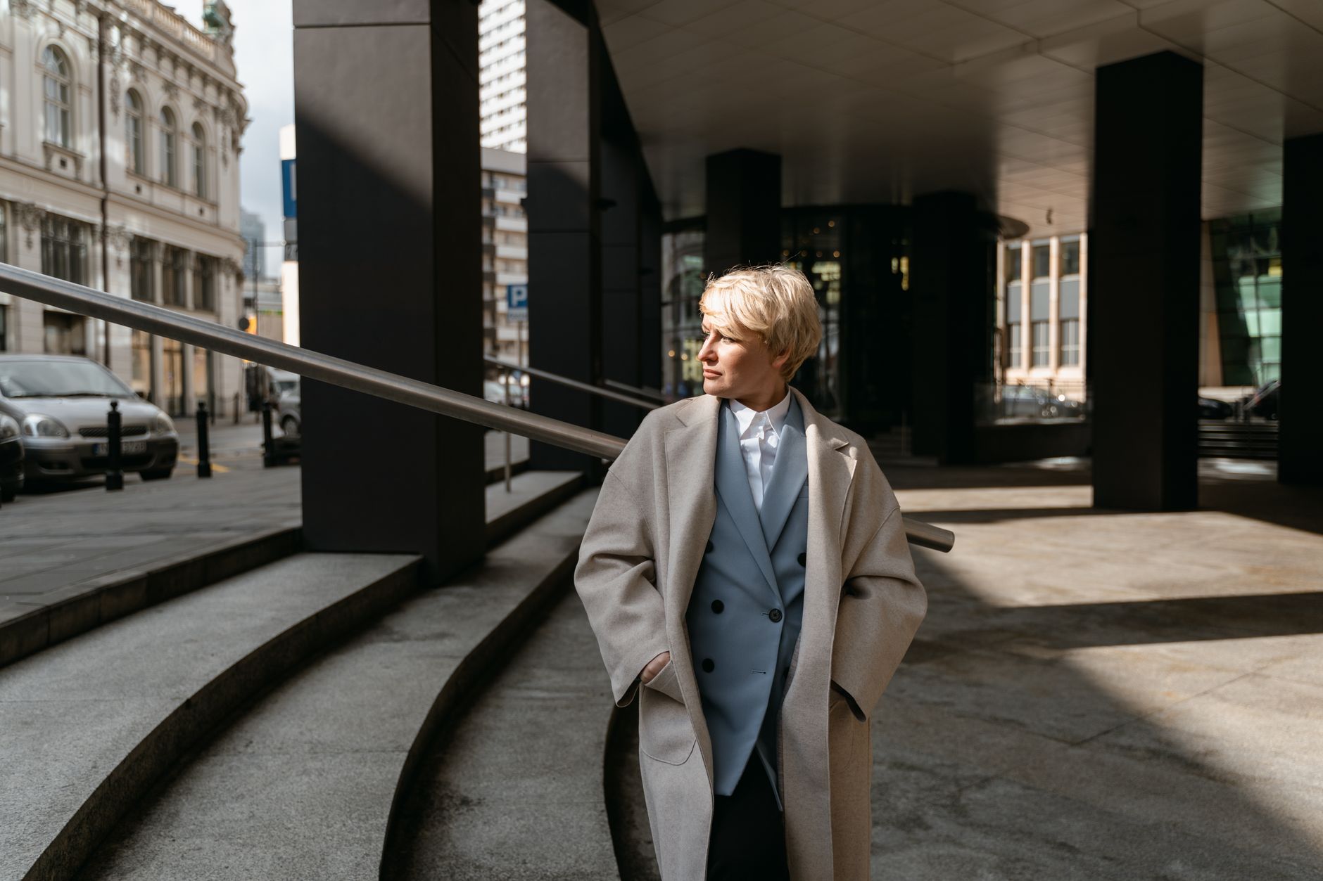 Person wearing a wide, asymmetric oversized coat on a city street, styled with straight-leg trousers and Chelsea boots