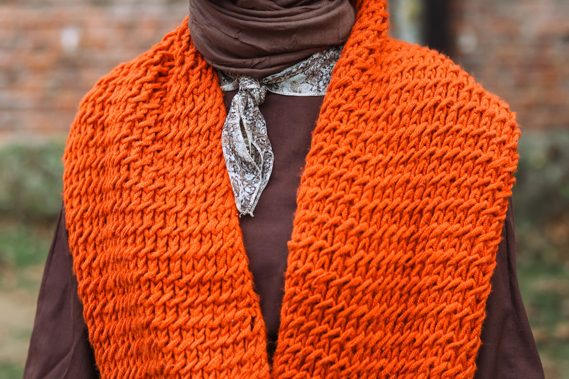 Close-up of a chunky knit wool scarf with visible ribbed texture and natural tonal variation in the fiber