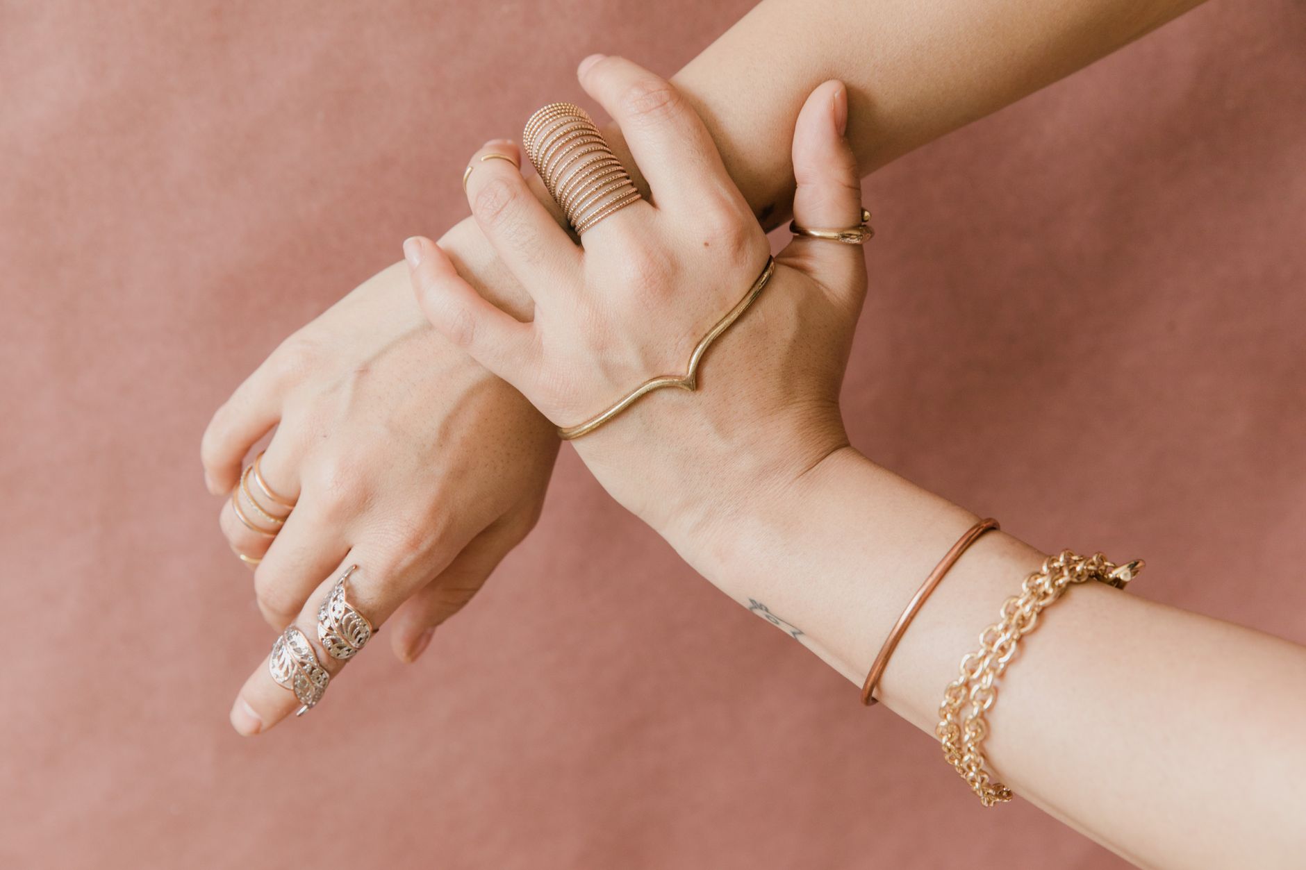 Layered bracelets and wraps stacked on a wrist against a neutral background