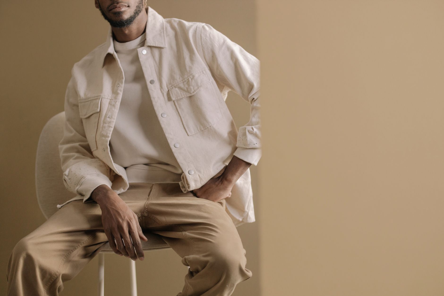 A model wearing a structured white shirt tucked into wide-leg trousers in a minimal styling context