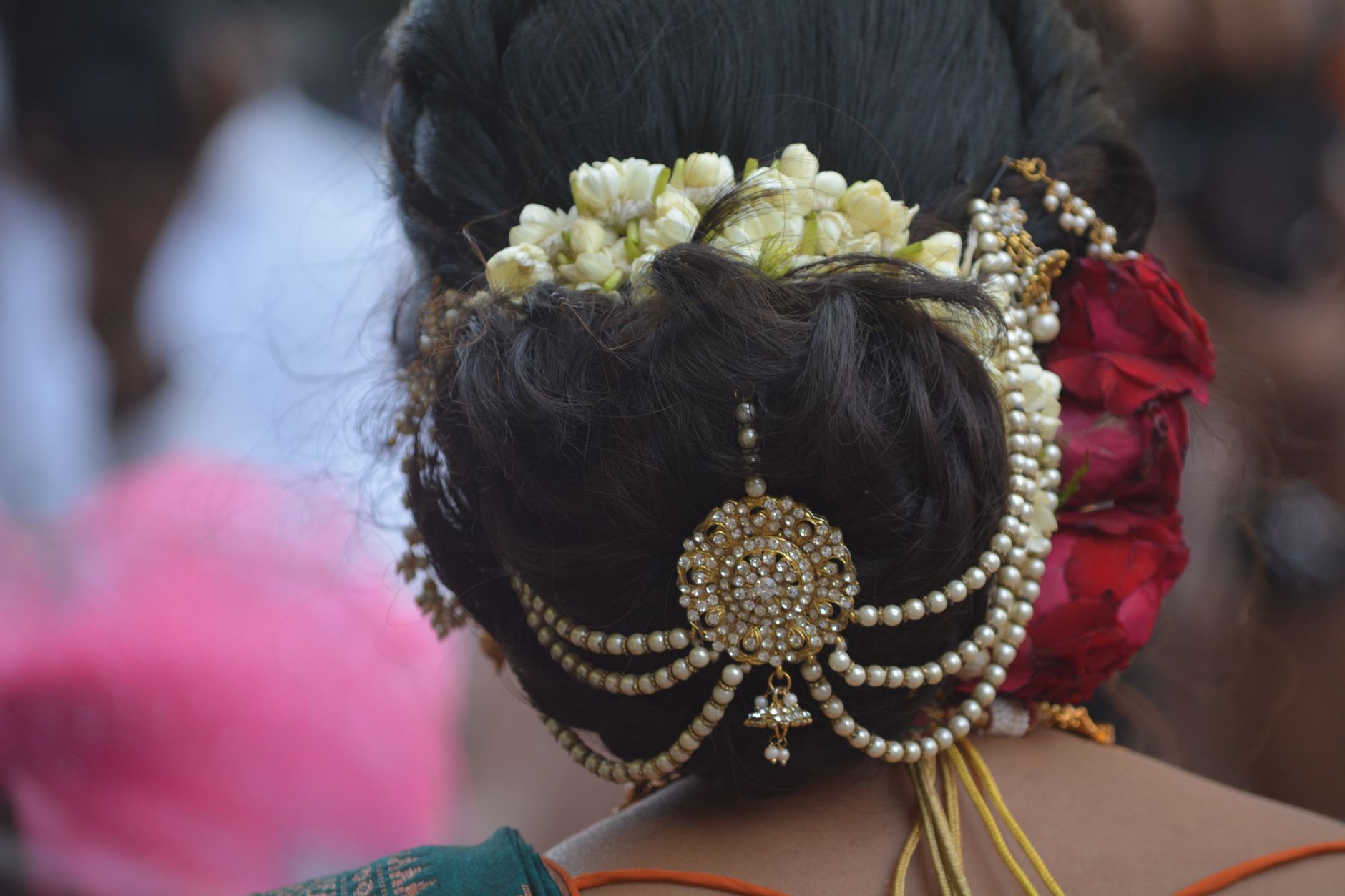 Detailed view of an intricate bridal braid adorned with small pearl and gold wire accents along the hairline