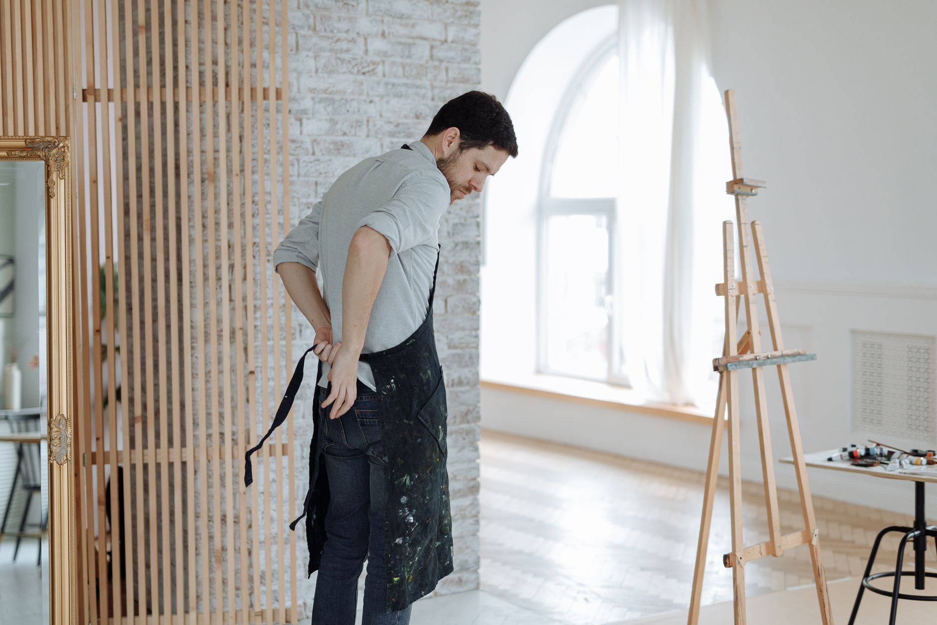 Close-up of a structured heavy canvas apron with deep front pockets laid flat on a wooden surface