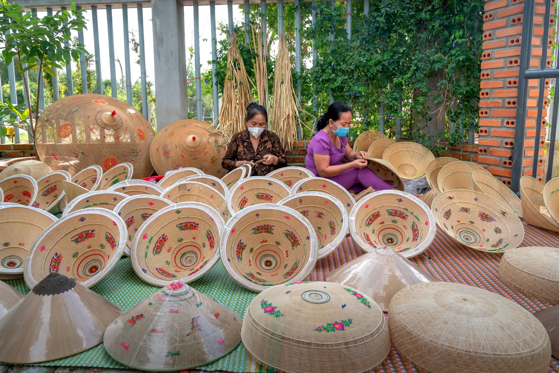 Artisan milliner shaping and finishing a straw hat by hand in a workshop