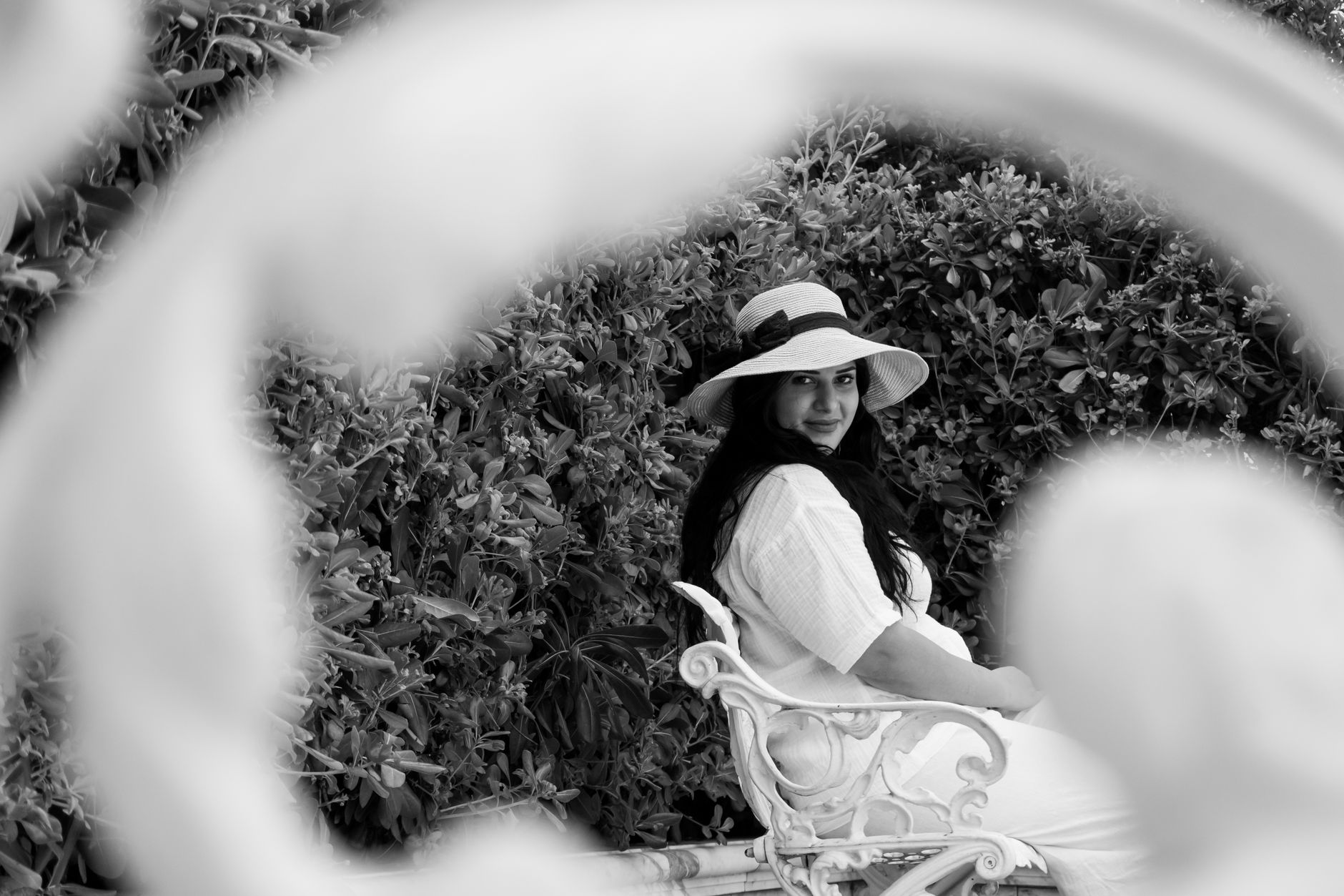 Elegantly dressed woman wearing a structured net and lace headpiece at a formal outdoor occasion