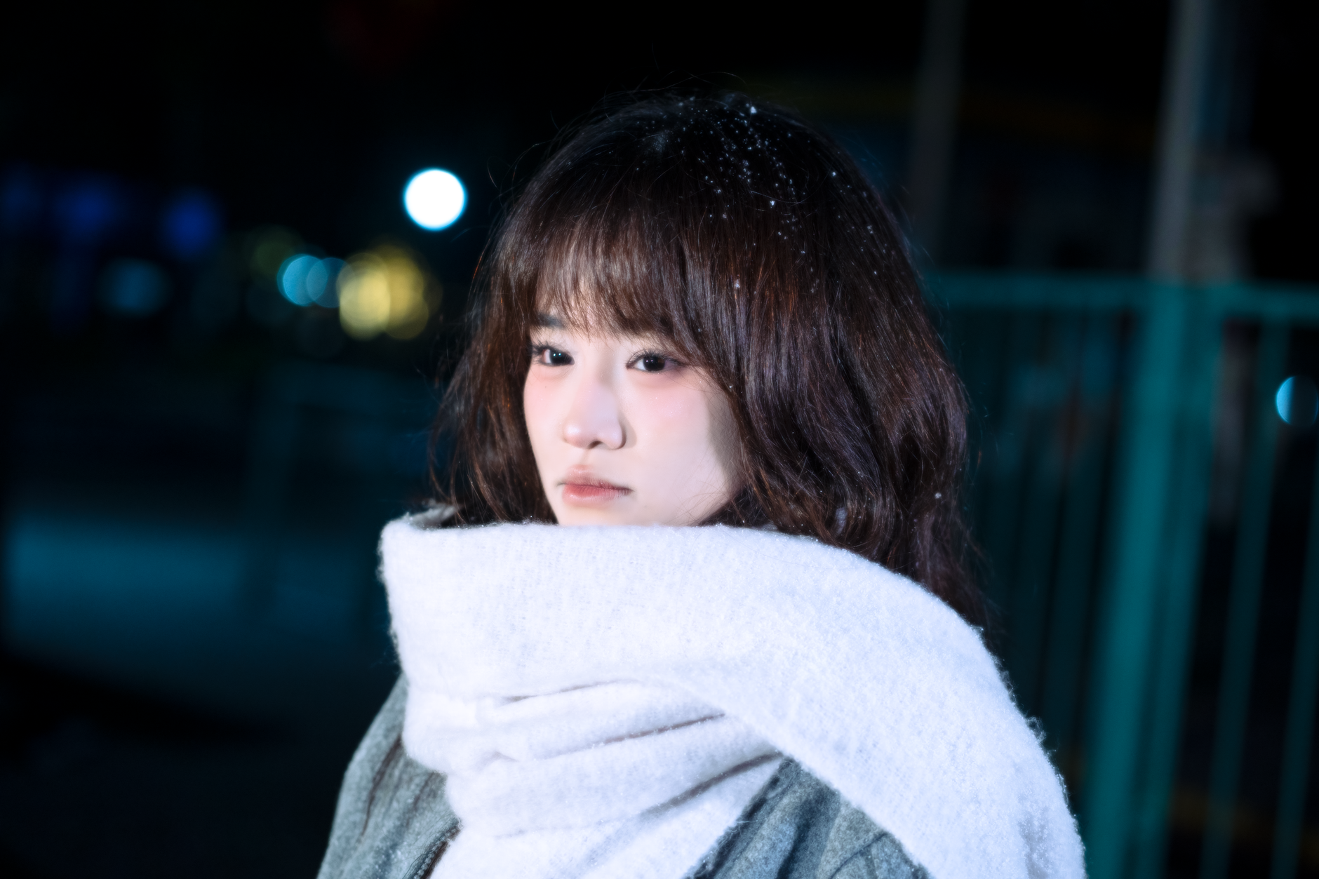 A woman wearing a long narrow scarf wrapped multiple times around her neck over a structured coat