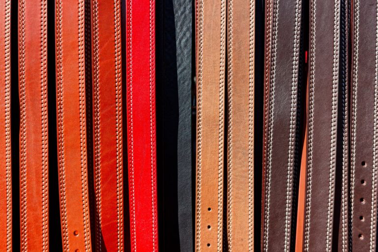 Close-up of a handcrafted leather belt with distinctive loop hardware laid flat on a wooden surface