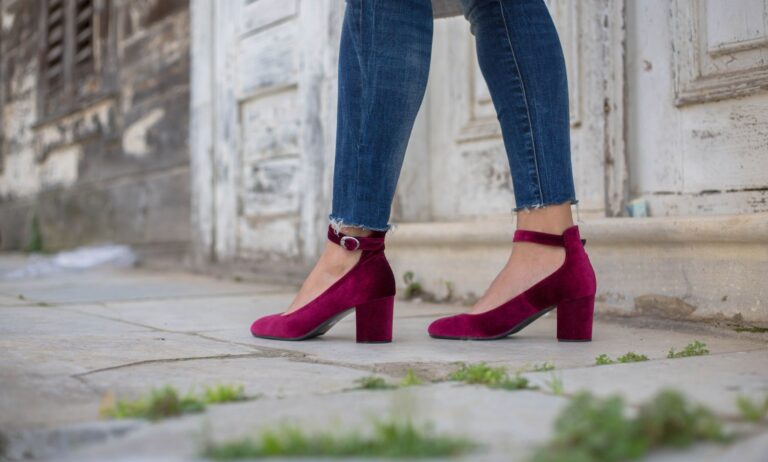 Close-up of a narrow leather ankle strap with a small brass buckle on a minimalist shoe