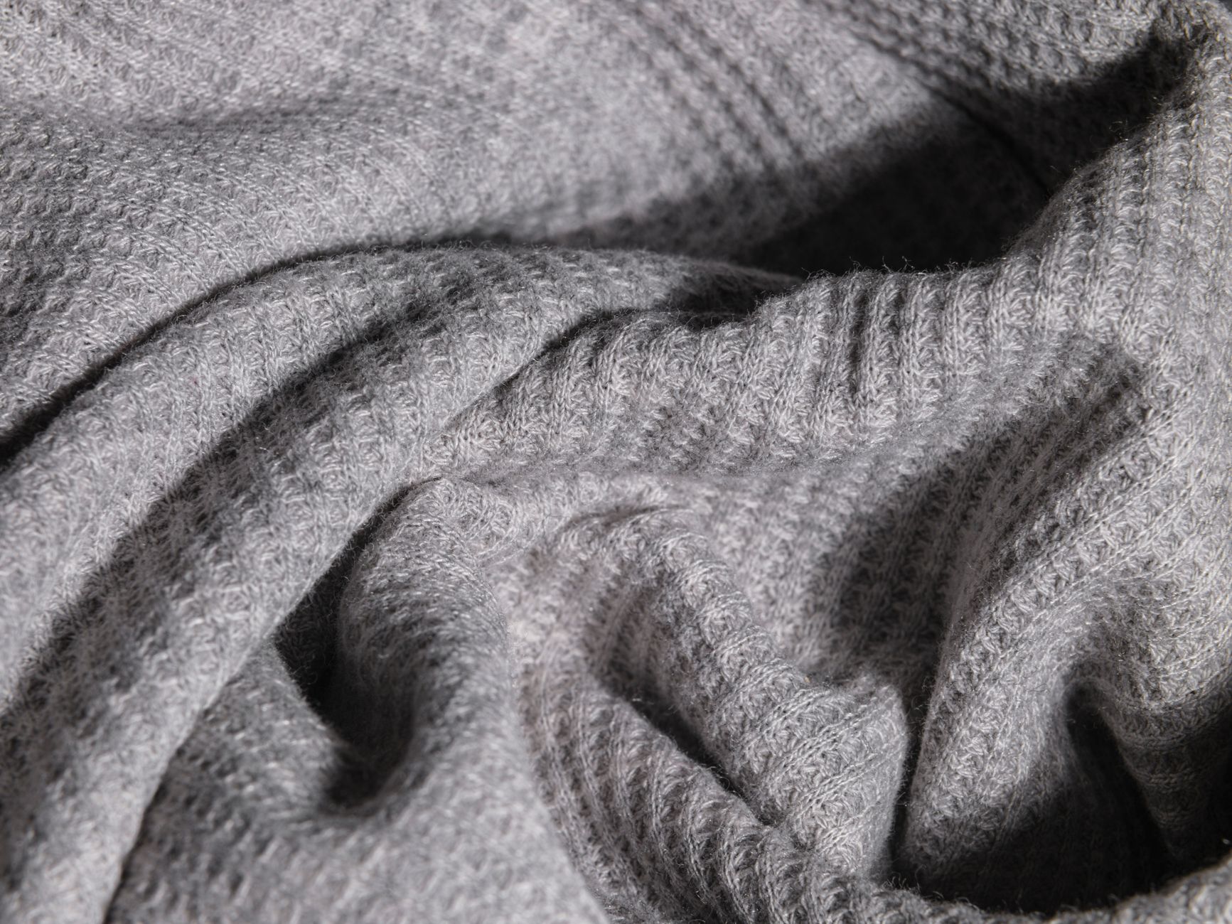 Close-up of quilted wool fabric with geometric stitching pattern in natural oatmeal tones