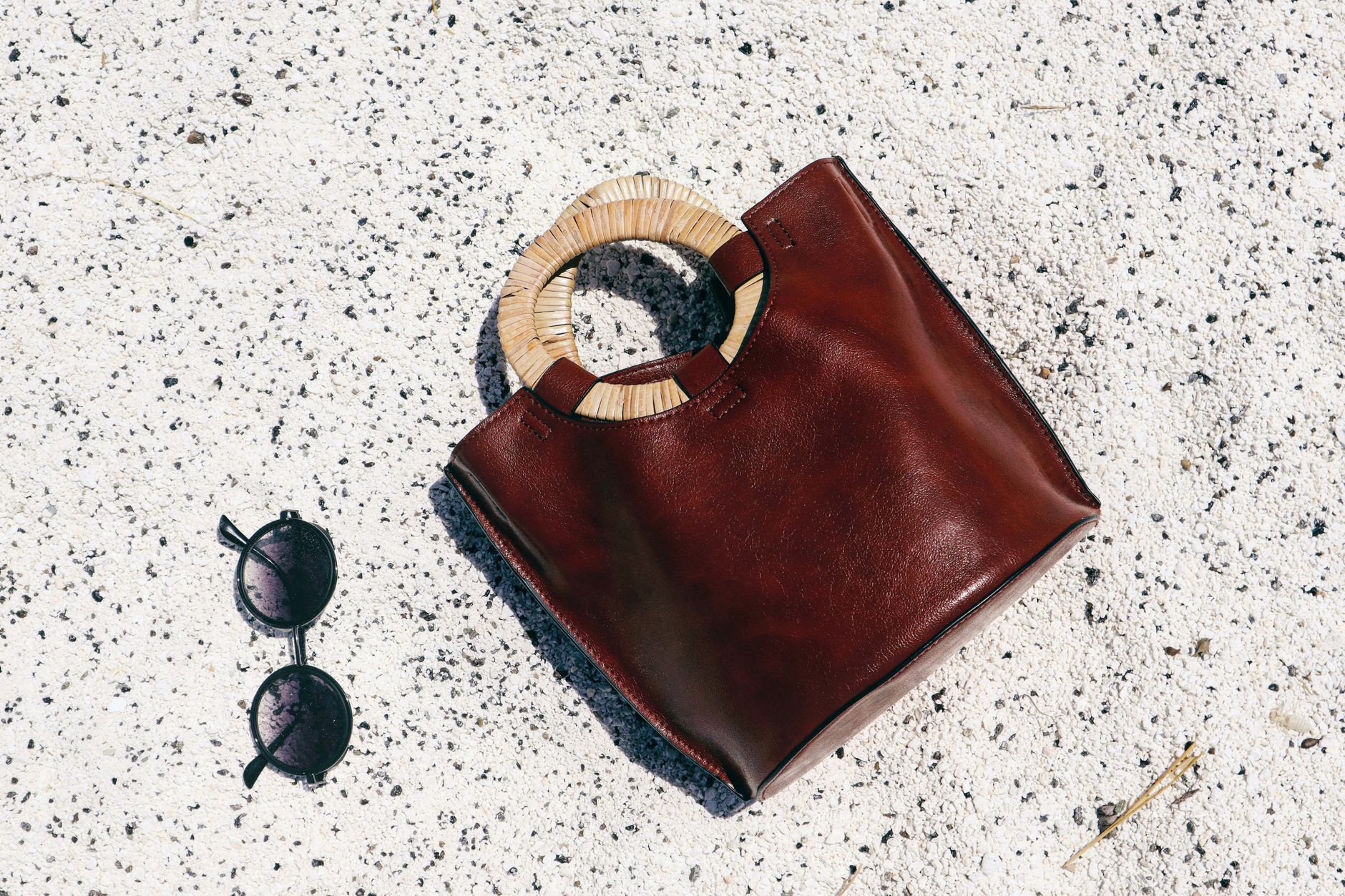 Close-up of a sculptural leather bag handle with ergonomic contours on a structured tote