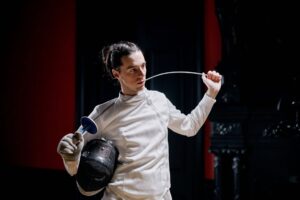 Fencing Jacket Plastron Hooks Are Quietly Clasping Into Avant-Garde Outerwear Close-up of metal clasp hardware on a structured sports jacket with overlapping fabric panels