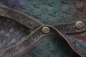 Close-up of a knitted sweater panel showing bold diagonal chevron stripes in navy and gold