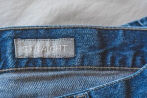 Close-up of metal buckle hardware on a tailored trouser leg, showing functional side-cinching detail