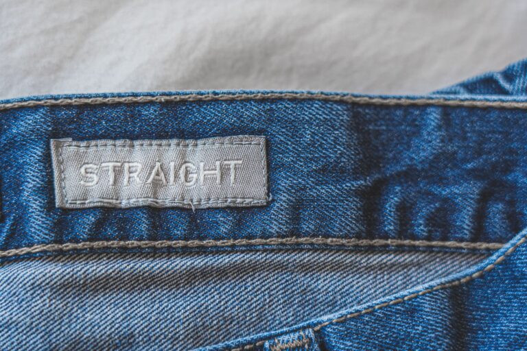 Close-up of metal buckle hardware on a tailored trouser leg, showing functional side-cinching detail