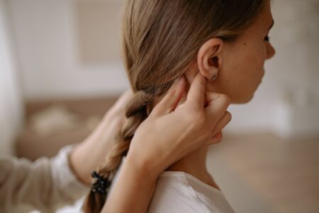 Close-up of tightly braided hair with small metallic cuffs placed at even intervals along the braid