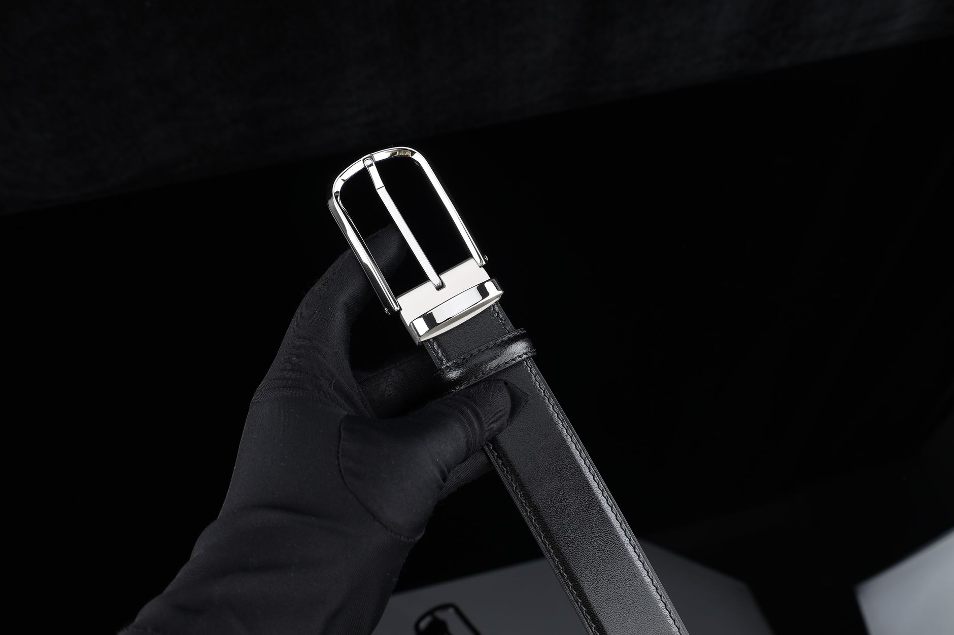 Close-up of leather strap with metal buckle hardware on a structured bag