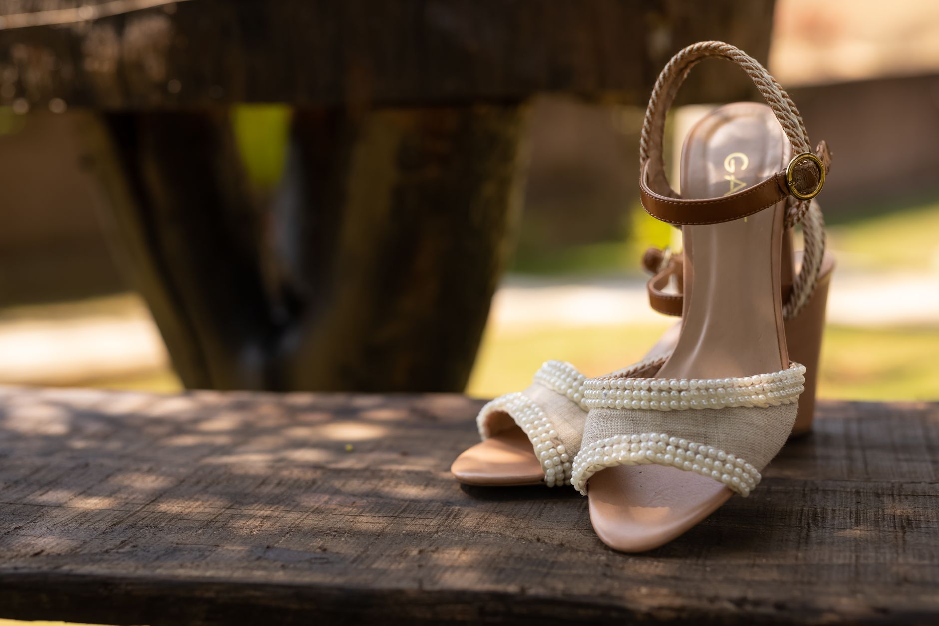 Close-up of a narrow leather strap with a small roller buckle worn around a bare ankle