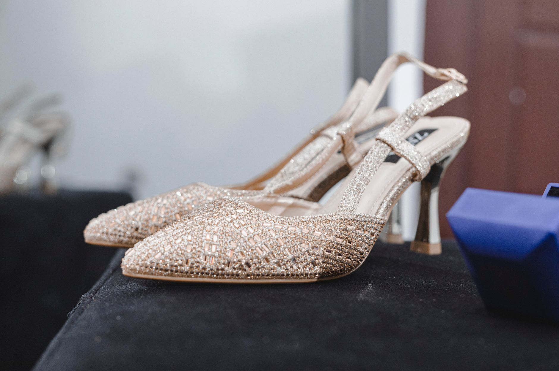 Designer footwear displayed on a minimal surface showing heel architecture and material detail