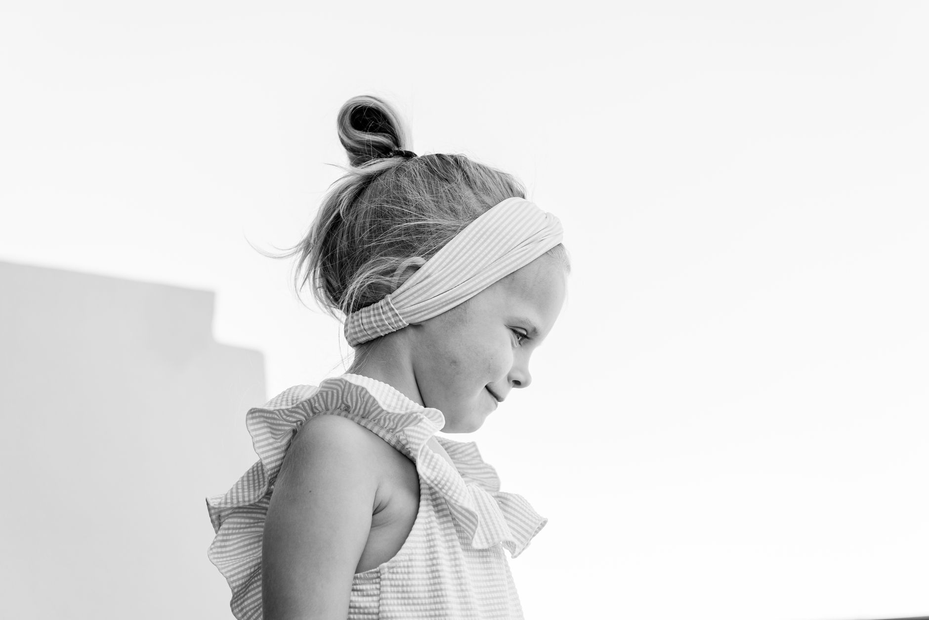 A model wearing a structured fabric headband as part of a clean, minimal outfit