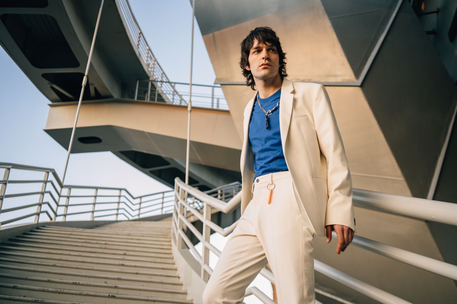 Model wearing an oversized polo shirt with a wide dropped collar styled with tailored trousers
