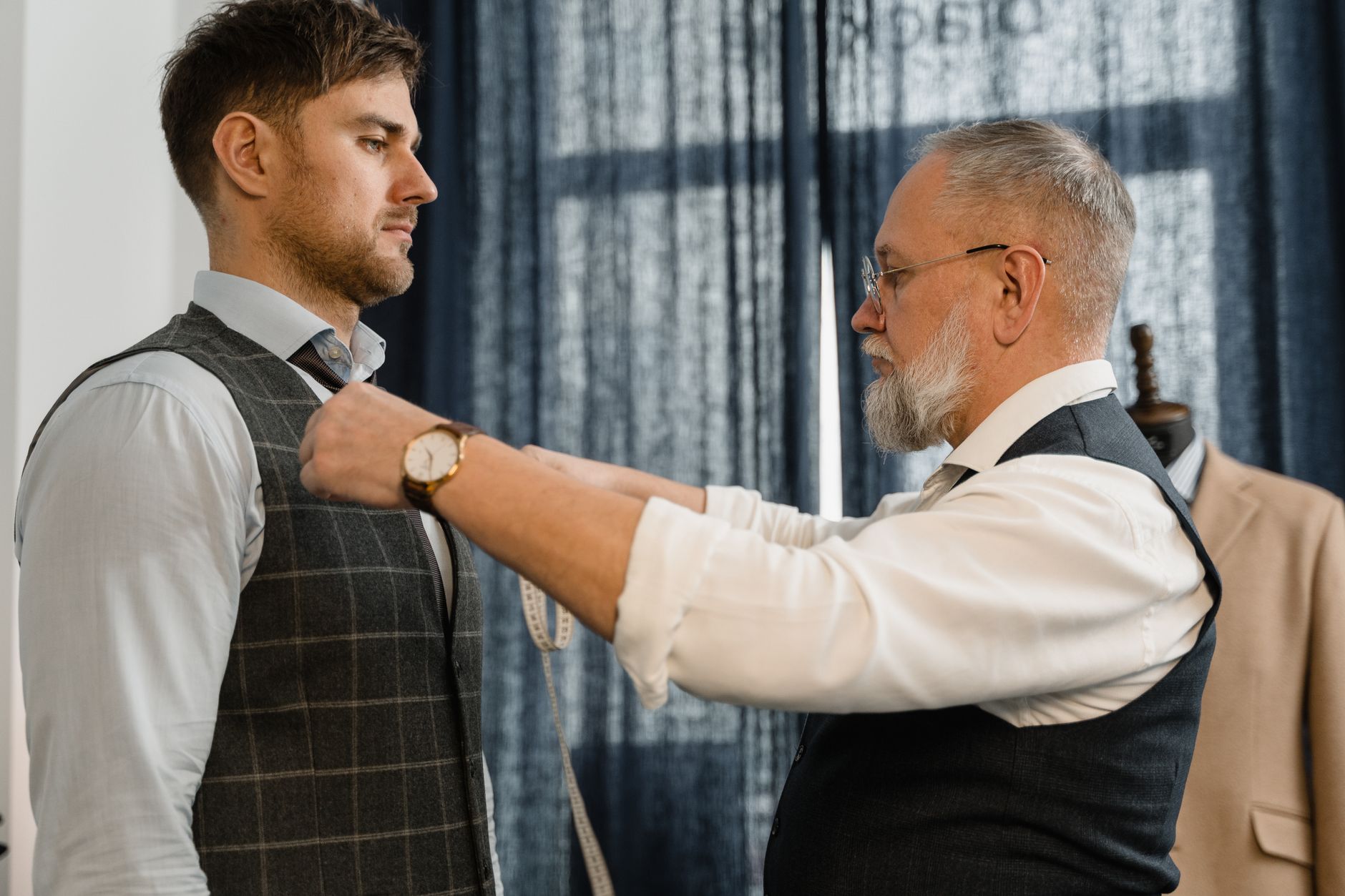 A tailor examining the hem construction of a wool blazer on a workbench