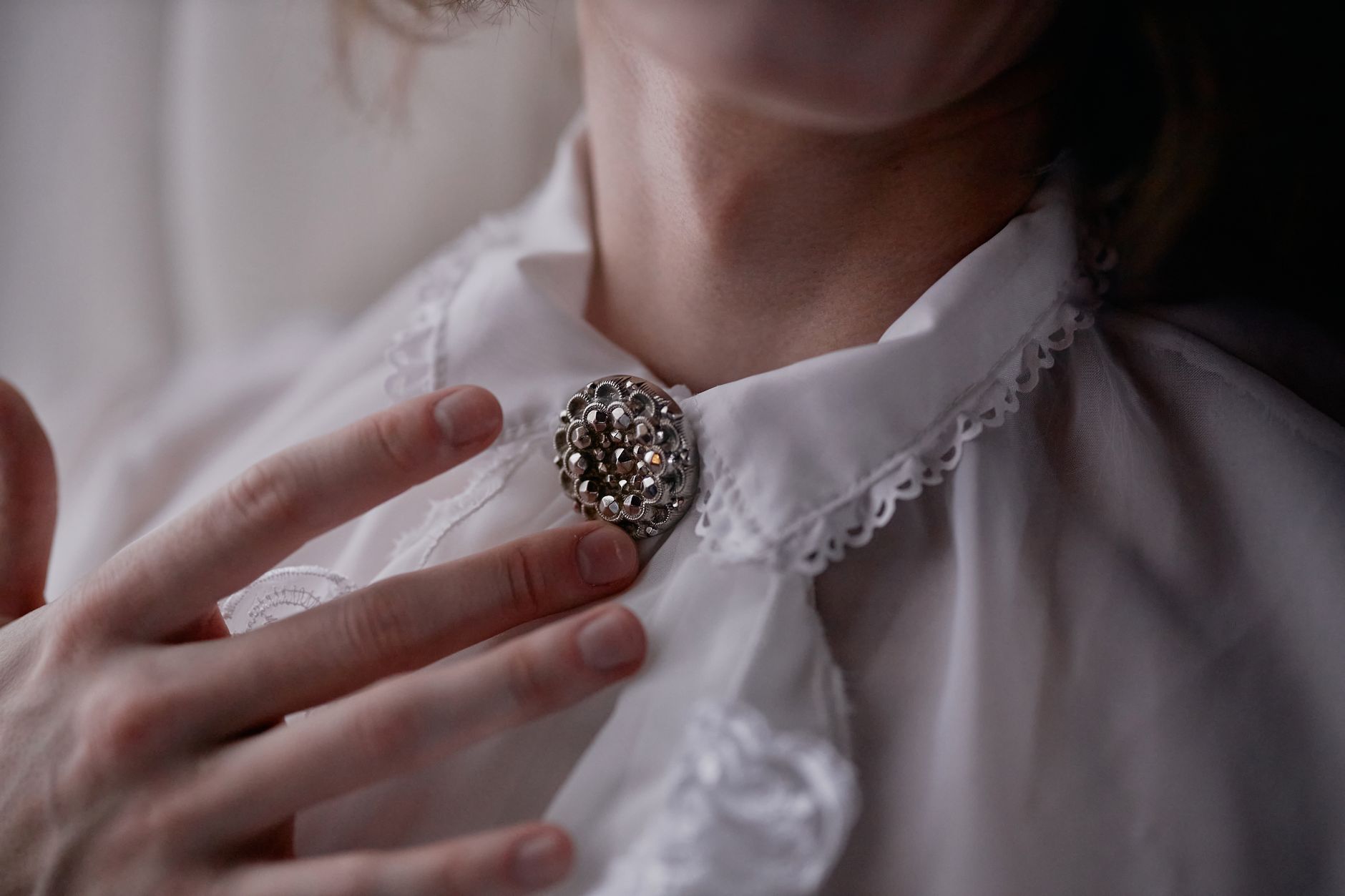 Flat-lay of geometric minimalist brooches in brass and neutral tones arranged on natural linen fabric