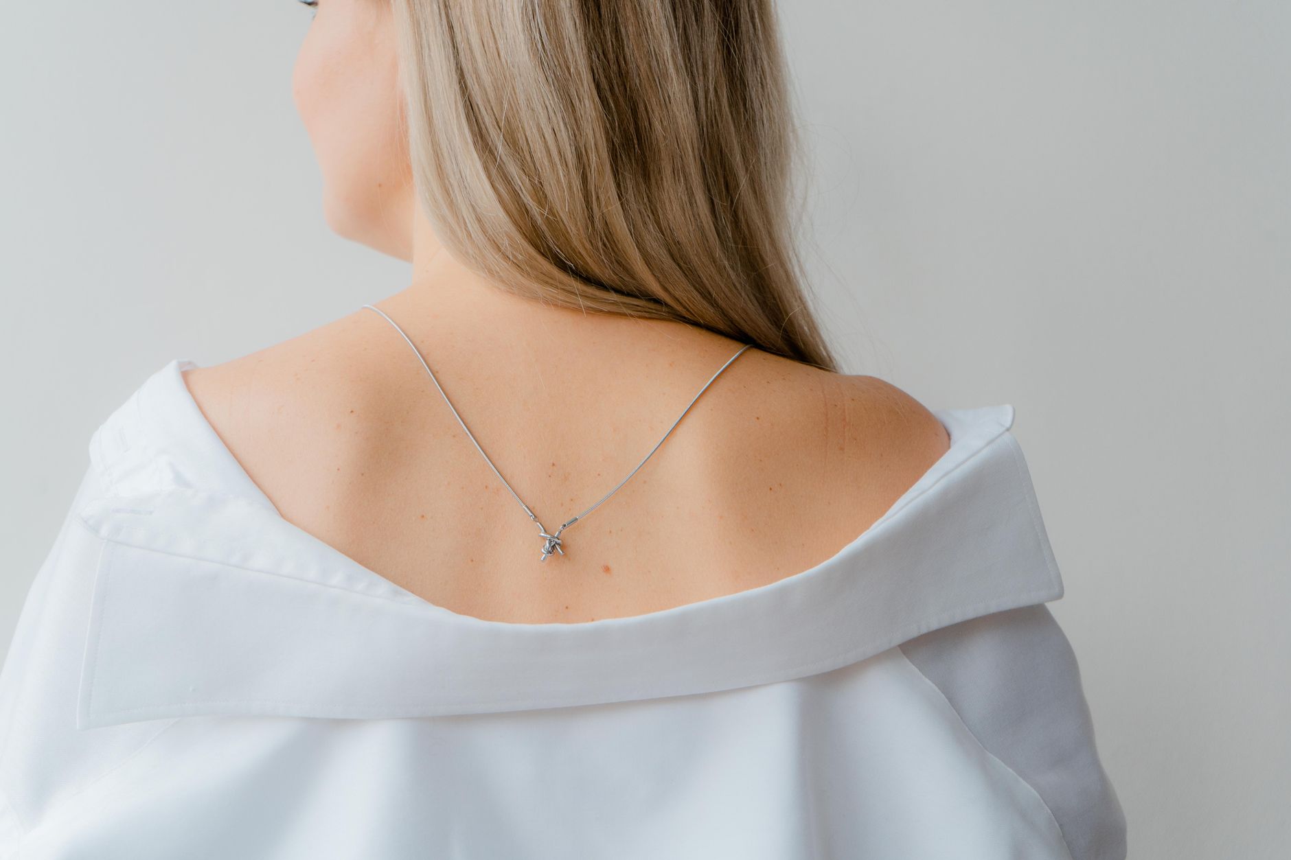 Woman wearing a simple metal loop choker against an open collar shirt