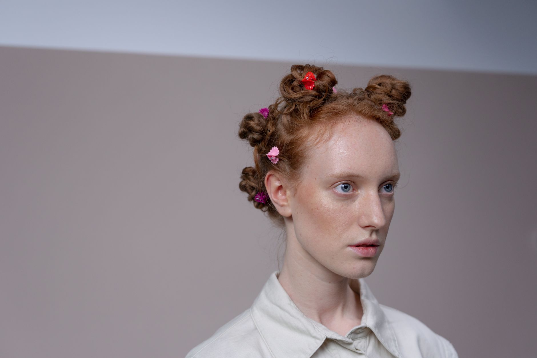Model wearing minimalist sculptural gold hair cuffs on loose textured hair against a neutral background