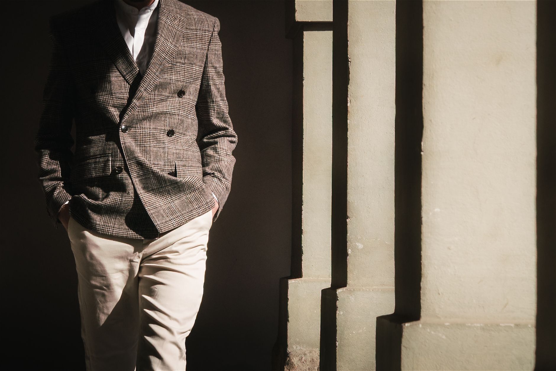 A man wearing a structured tailored jacket with visible hem detail in a neutral setting