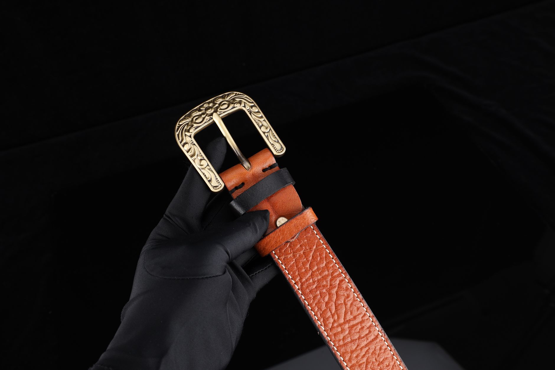 Brass and vegetable-tanned leather hardware detail on a clothing waistband