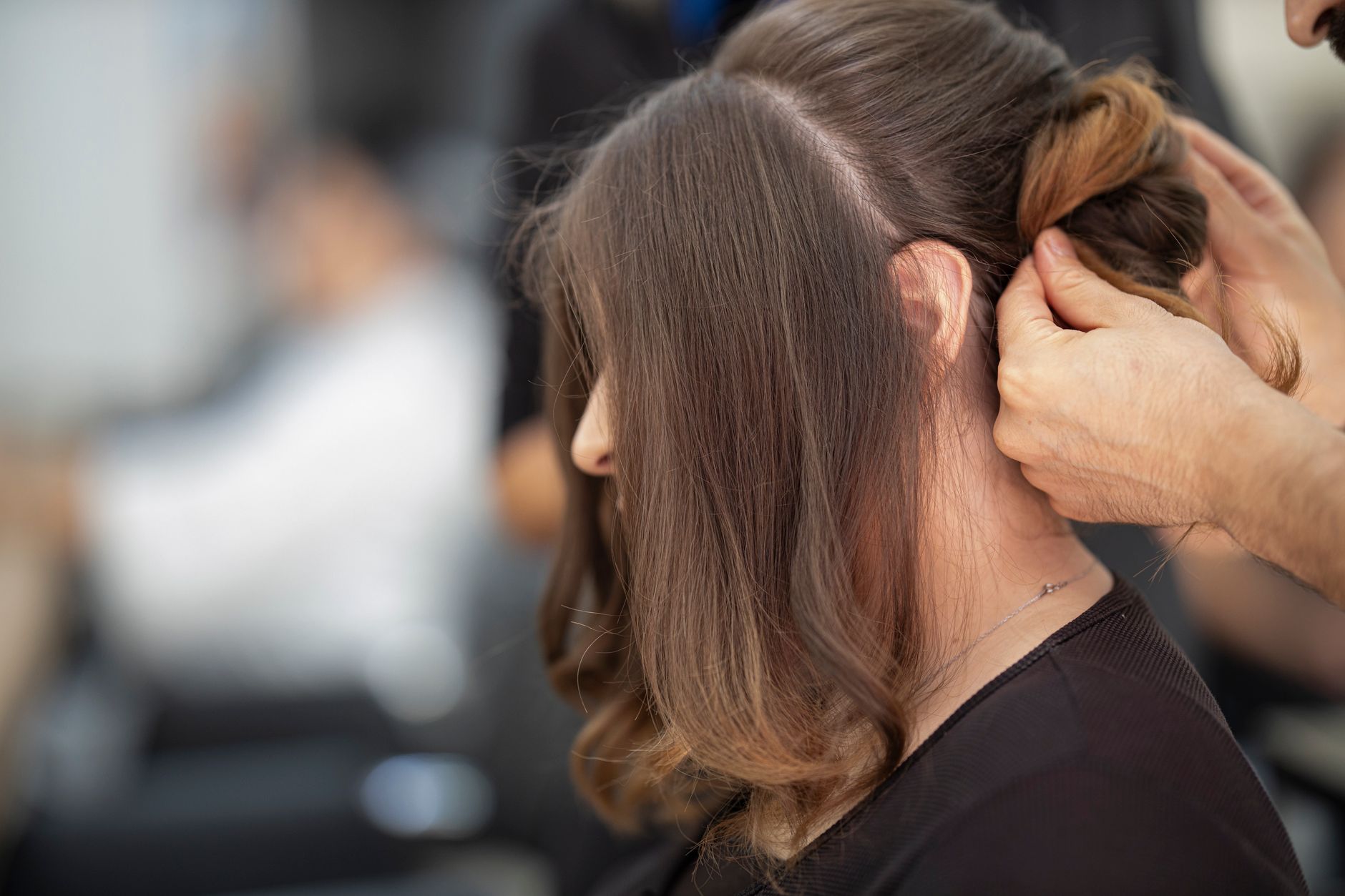 A woman with a sleek low bun secured by a crystal-studded barrette at the nape of her neck, photographed from behind