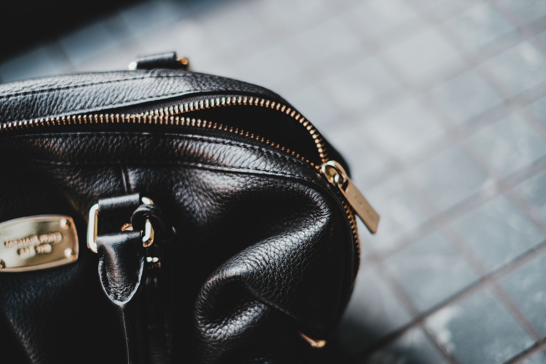 Structured luxury handbag with textured handle resting on a neutral surface