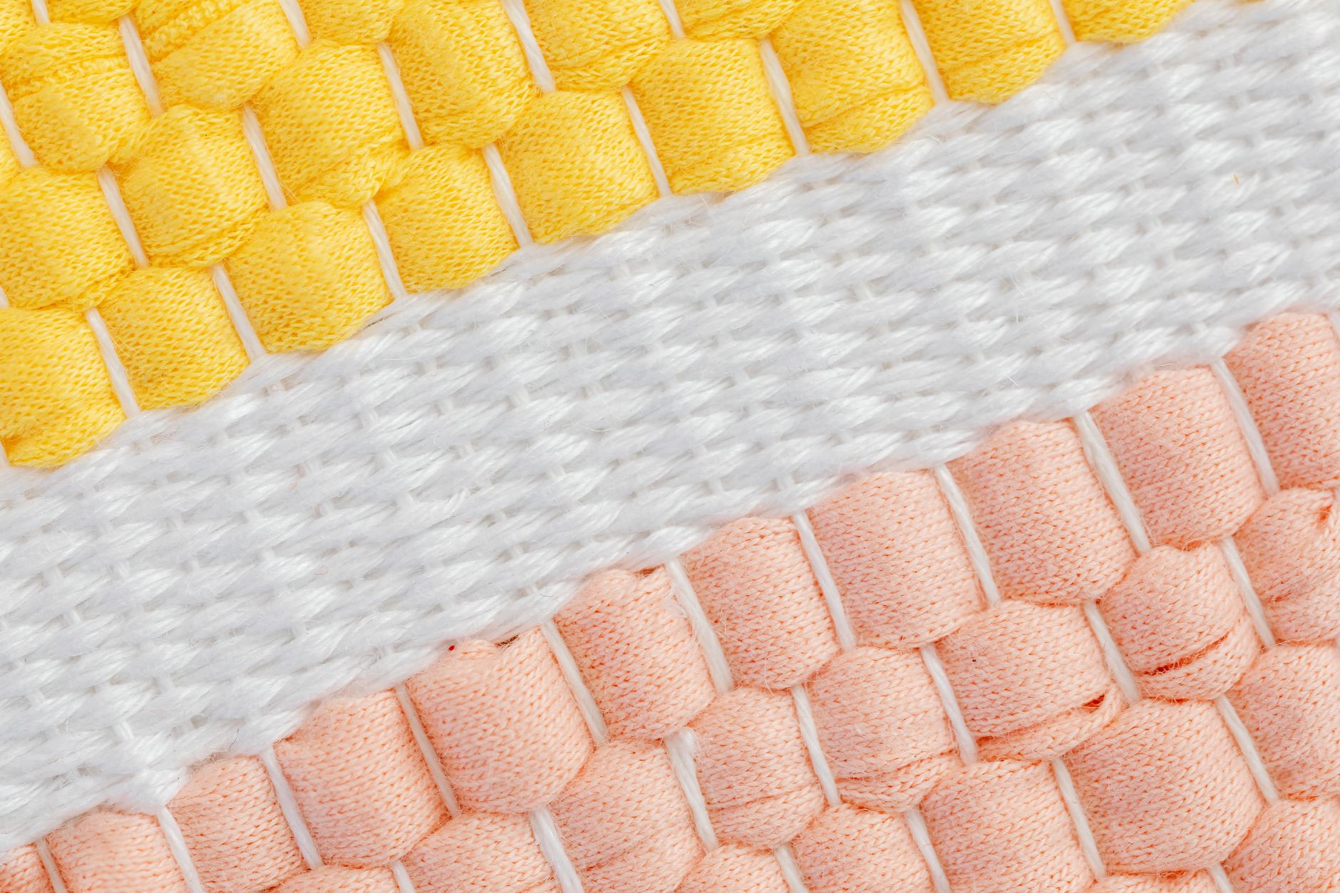 Close-up of yarn threaded over loom knitting pegs in a regular pattern