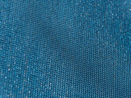 Close-up of a shimmering metallic woven fabric with a tight, structured weave pattern