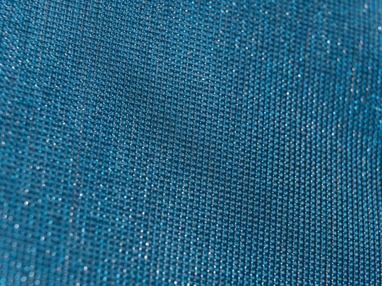 Close-up of a shimmering metallic woven fabric with a tight, structured weave pattern