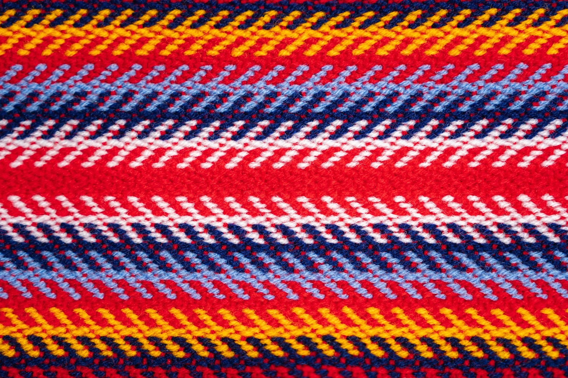 Close-up of a woven canvas belt with metal edge hardware detail against textured fabric