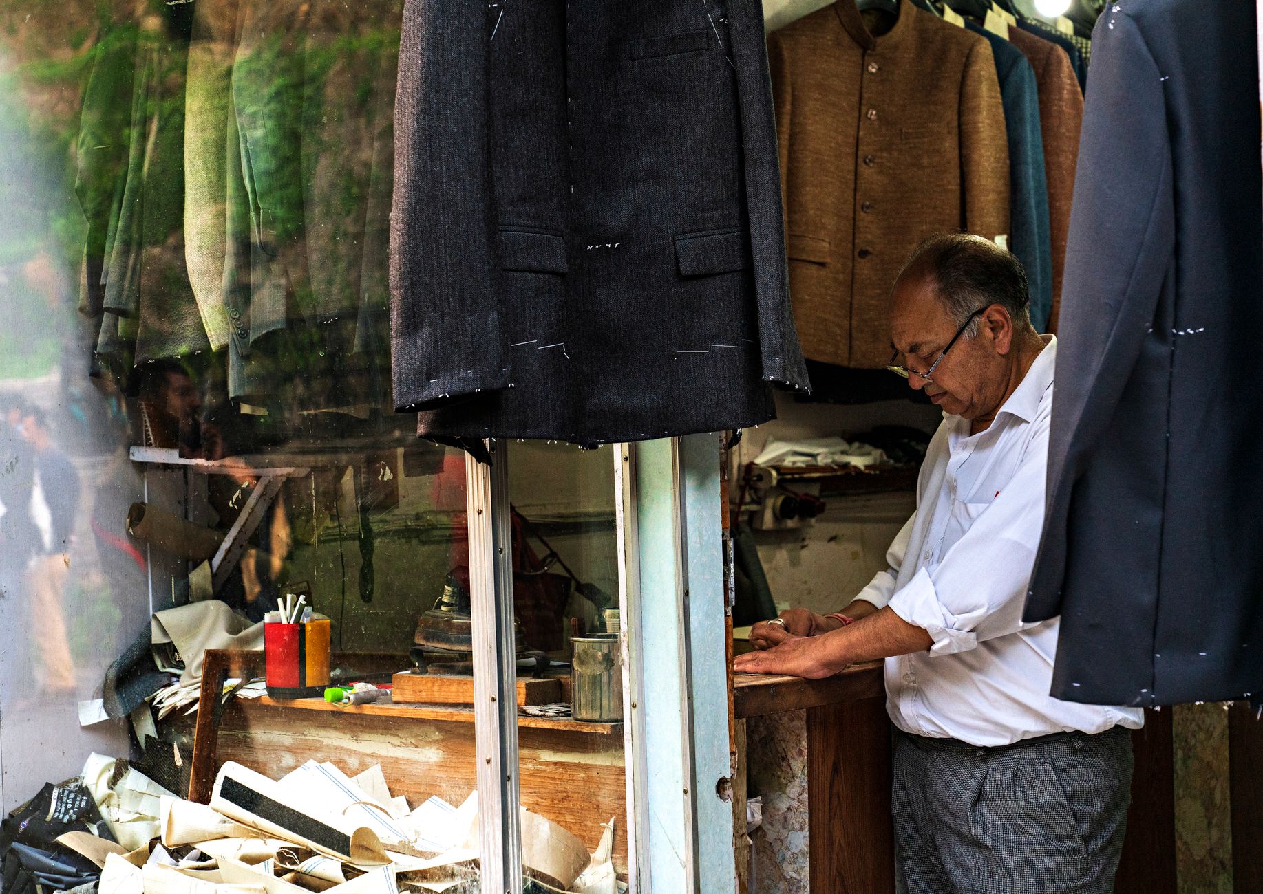 A tailor working on a structured jacket in a formal tailoring workshop