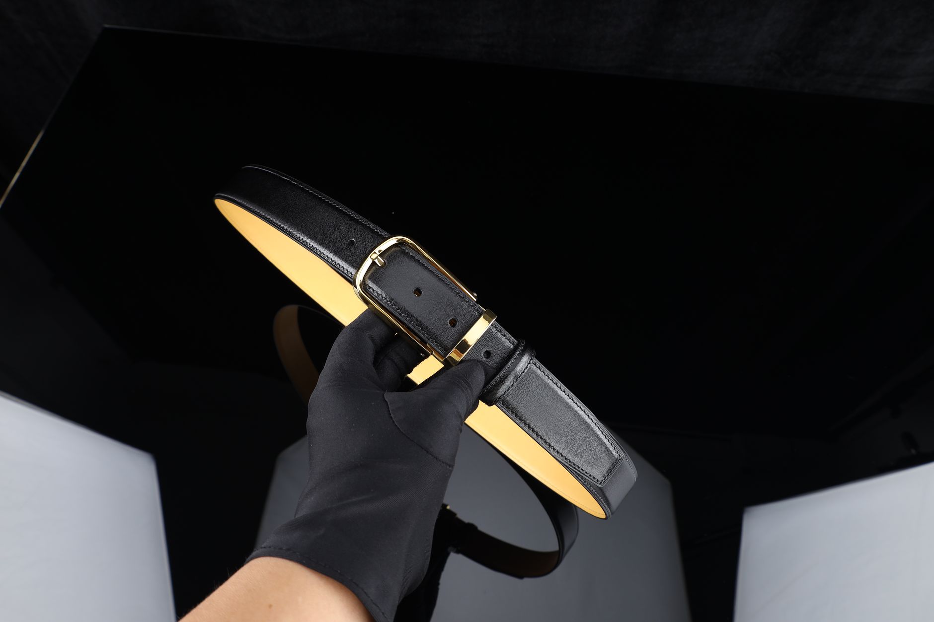 Structured leather belt with metal D-ring hardware detail on the back panel