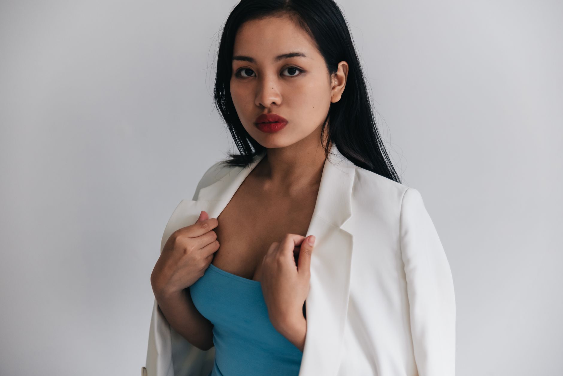 A structured high-collar blazer with metal hardware fastening at the throat, photographed against a neutral background