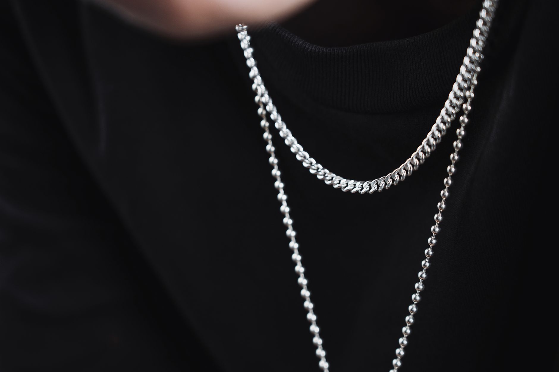 Minimalist gold chain necklace with geometric hardware connector laid flat on a neutral surface