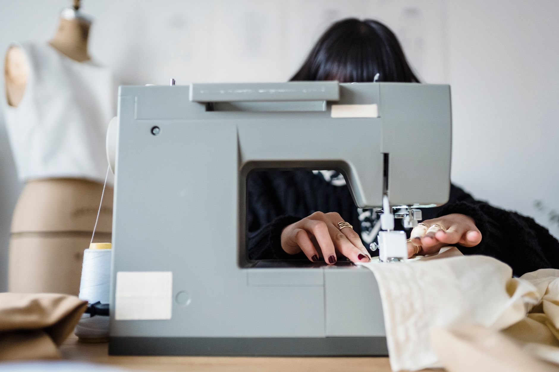 A tailor working on a structured garment sleeve at a fashion atelier workbench