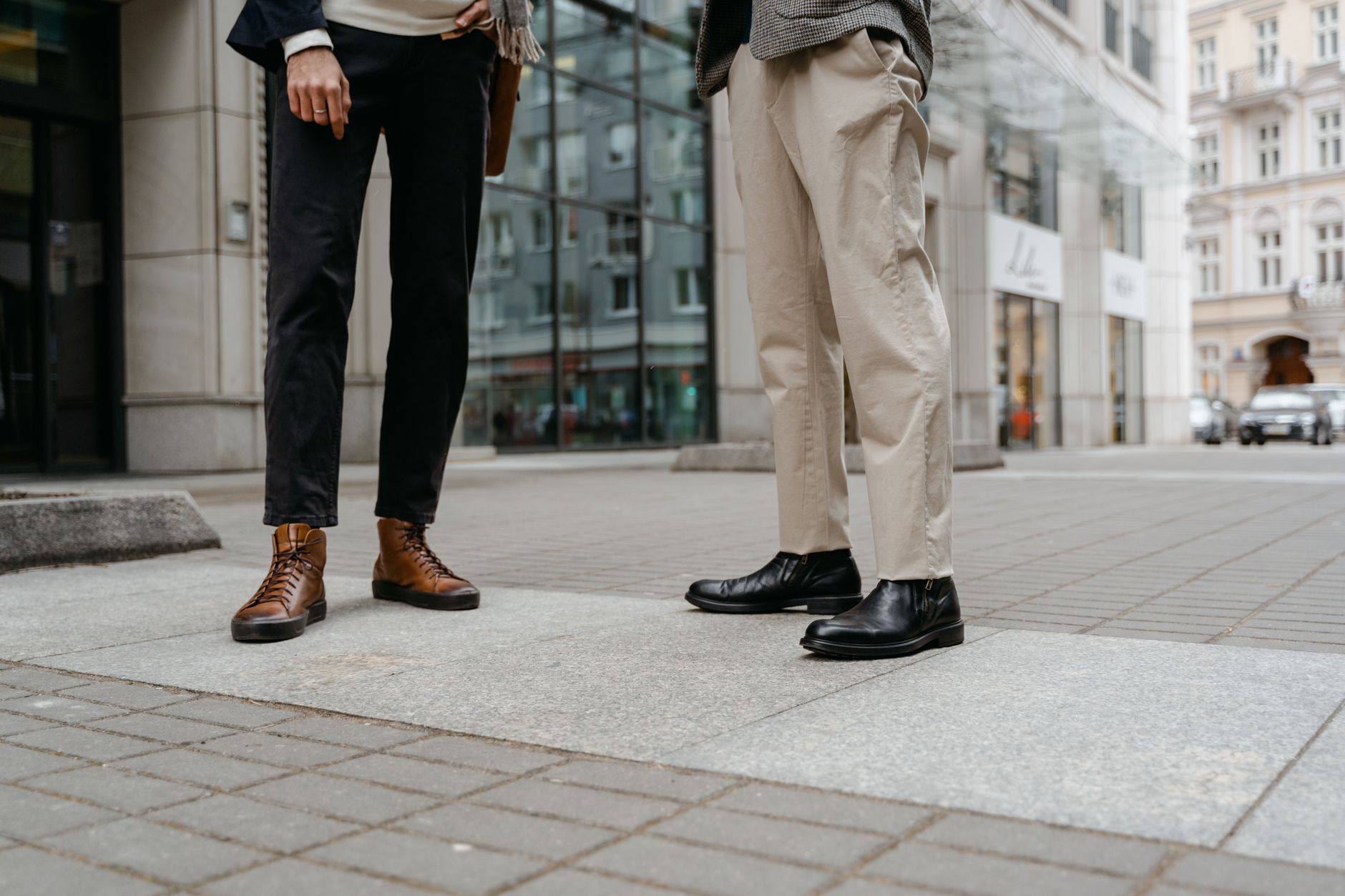 Model wearing cropped tailored trousers with visible button tab detail at the hem
