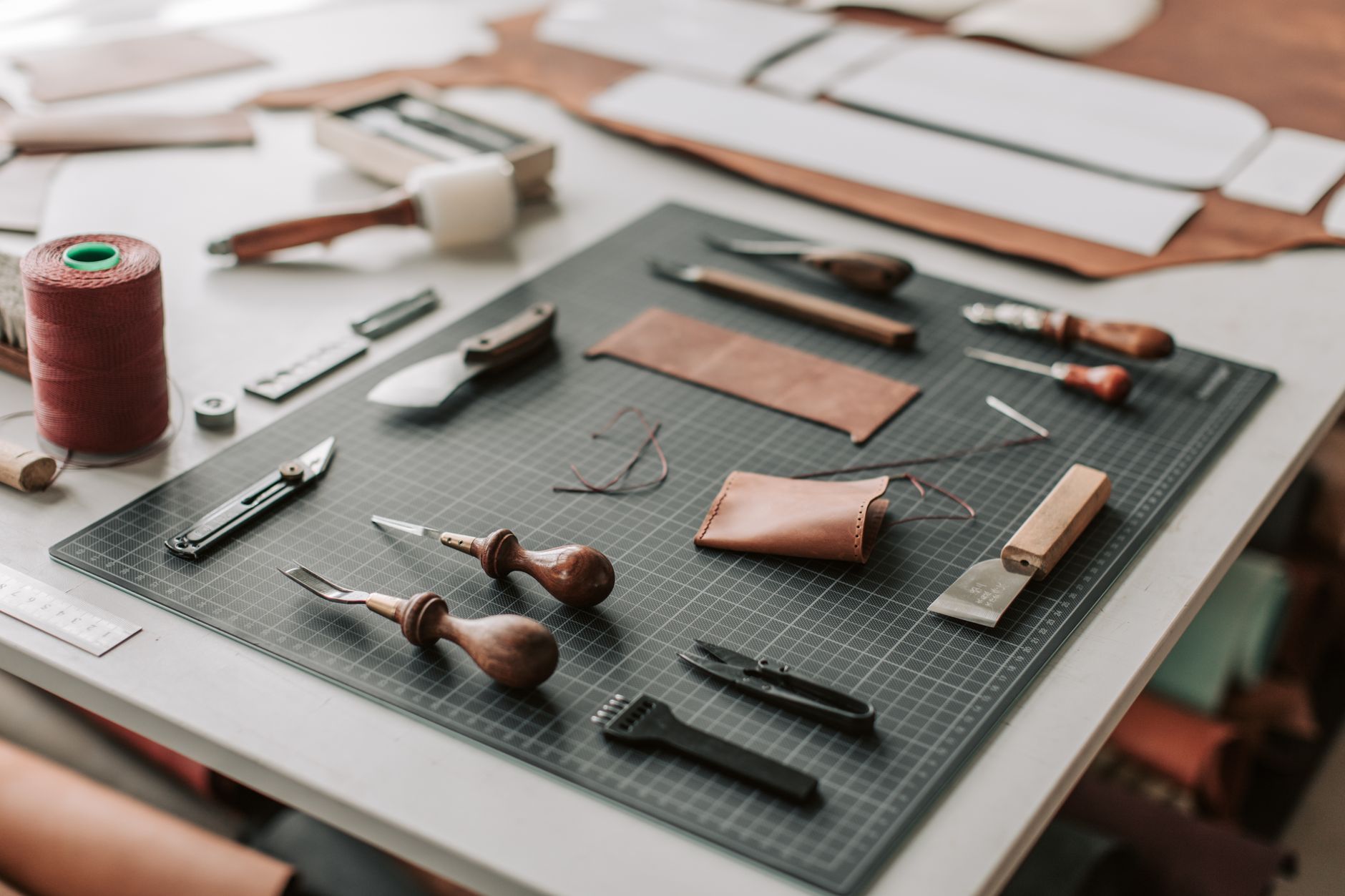 Craftsperson cutting a precise slot in a leather belt tab on a workbench