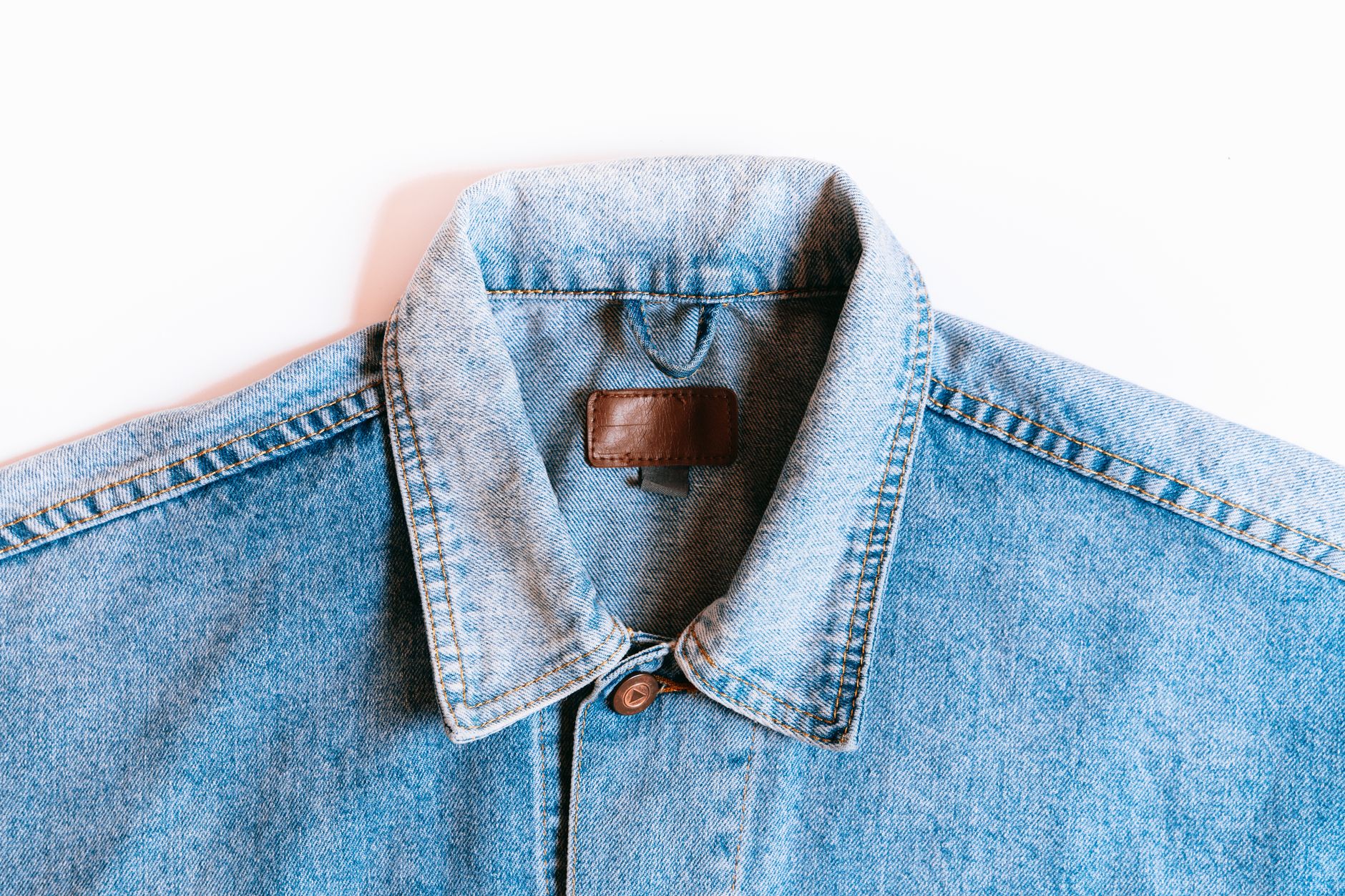 Detail shot of decorative metal arch hardware on a tailored coat collar in antique brass finish