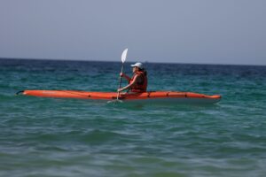 Close-up of a kayak paddle showing offset feathered blade angles above calm flat water