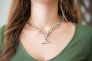 Close-up of a minimalist silver chain necklace with geometric link detailing laid flat on a light surface